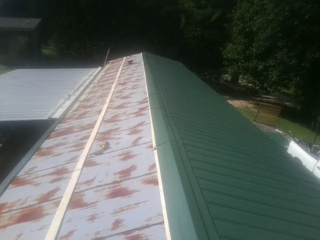 Old rusted panels beside newly installed green metal roofing — Wind Damage Roof Repair by Roofing Brothers in Crystal Bay