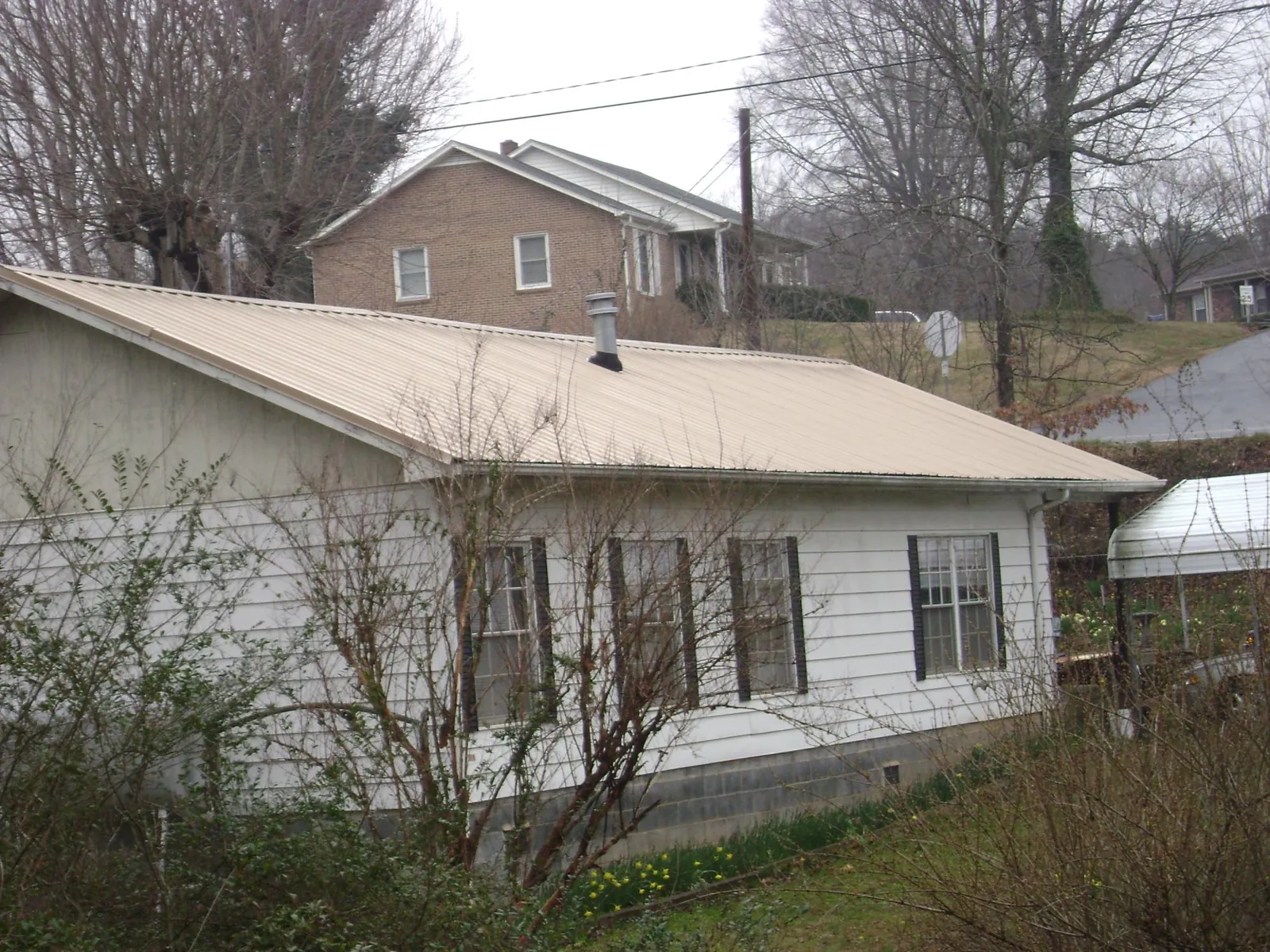 Tan metal roof on a white sided house set into a hillside — Commercial Roofing by Roofing Brothers in Crystal Bay
