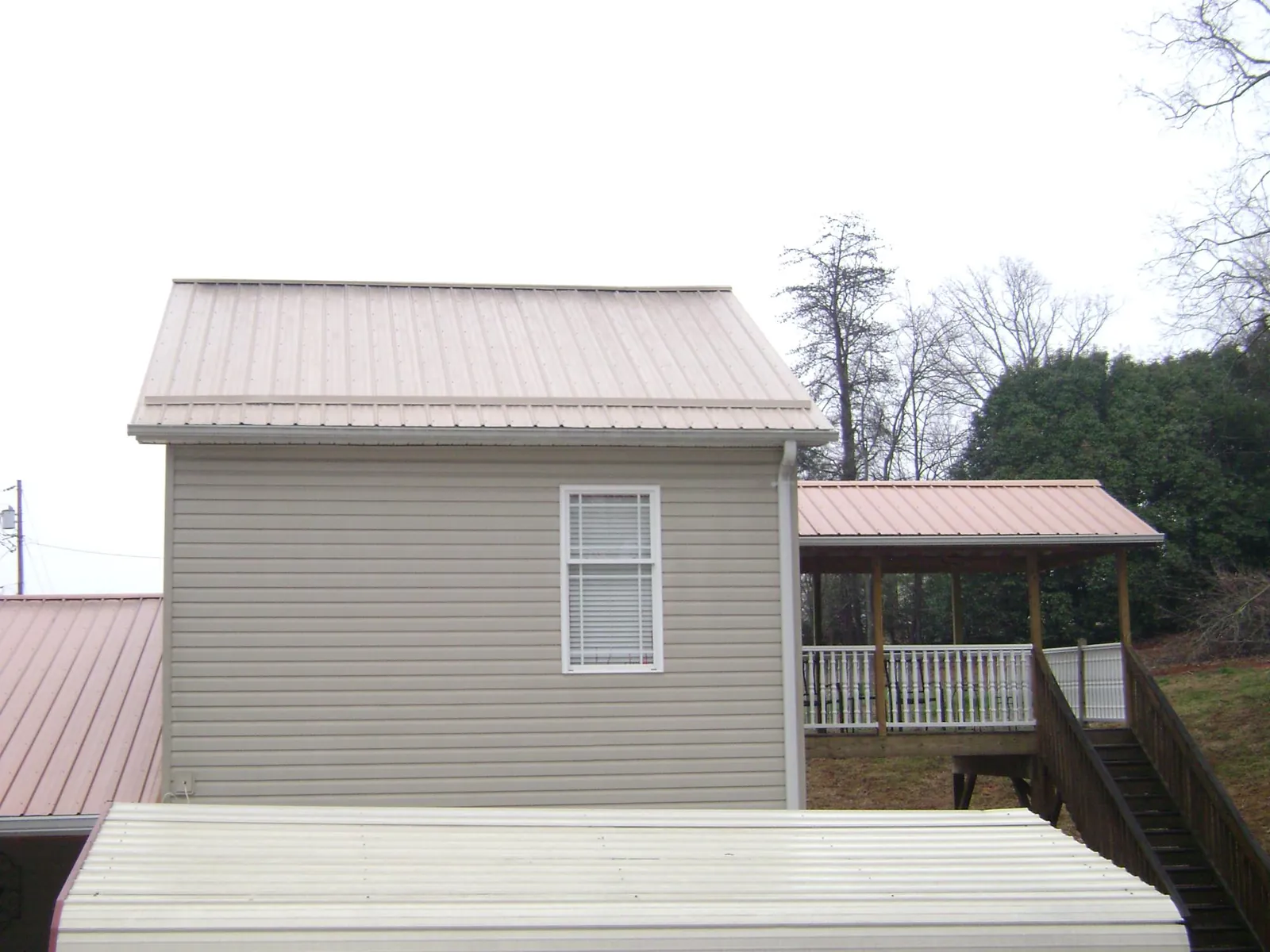 Tan metal roofs on a two story addition and attached porch, from a Roof Replacement job in Crystal Bay