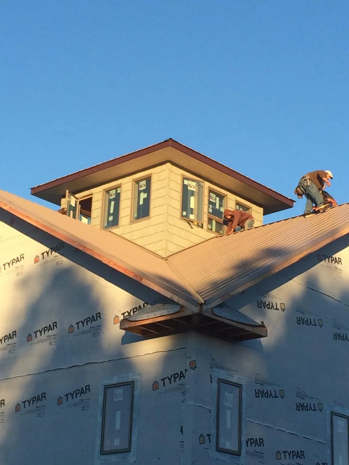 Roofers working around a rooftop cupola on a new metal roof at sunset — Roof Waterproofing in Crystal Bay by Roofing Brothers